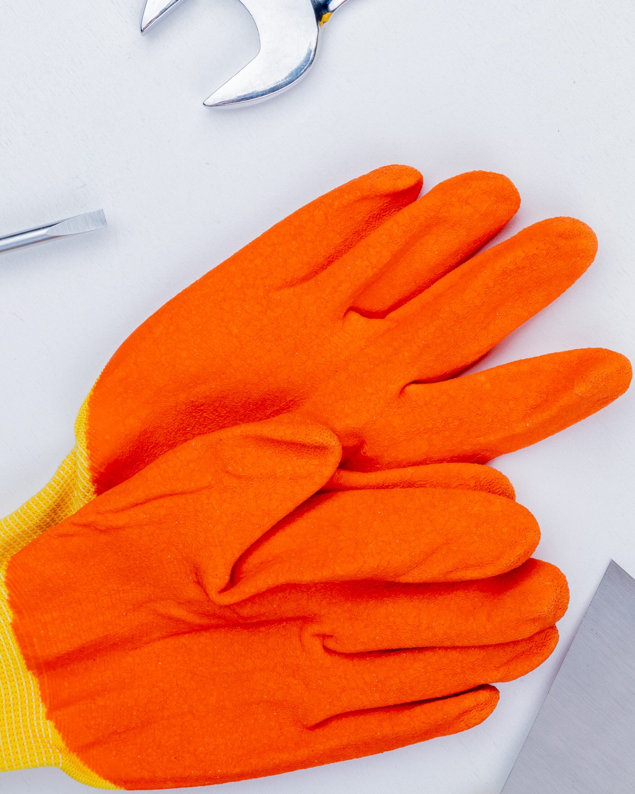 close-up view of gloves with safety helmet wrench and screwdriver on white background